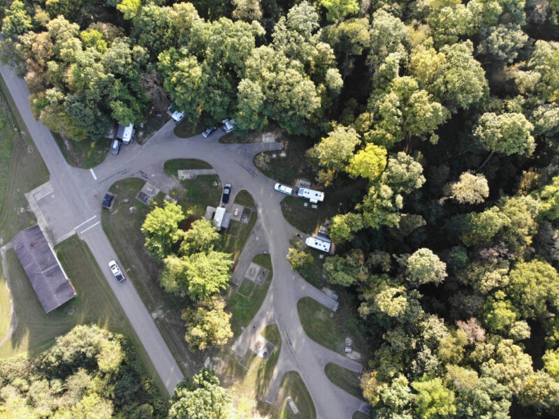 an overhead shot of a campground with rvs parked at sites surrounded by trees