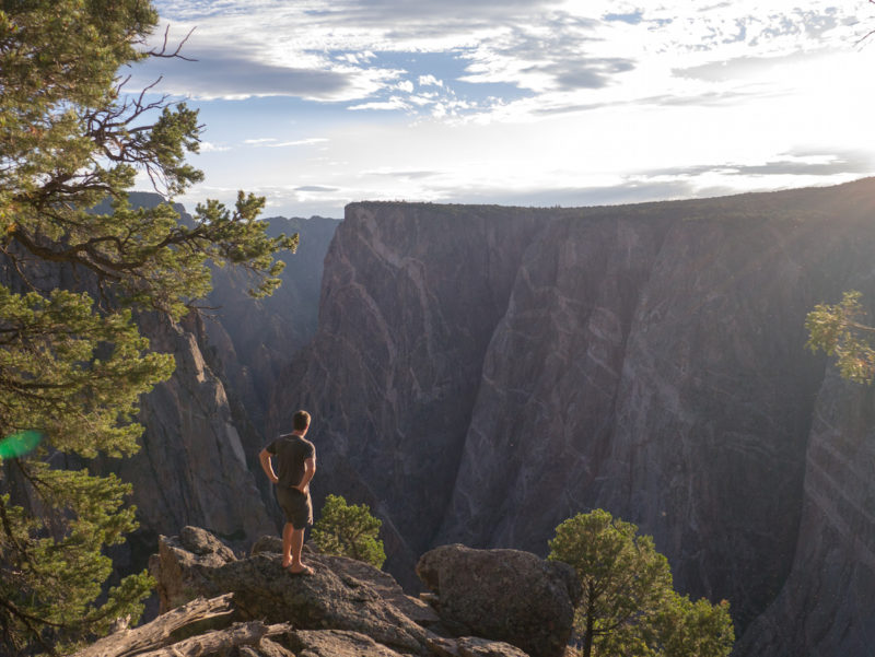 a person stands on the edge of a large canyon