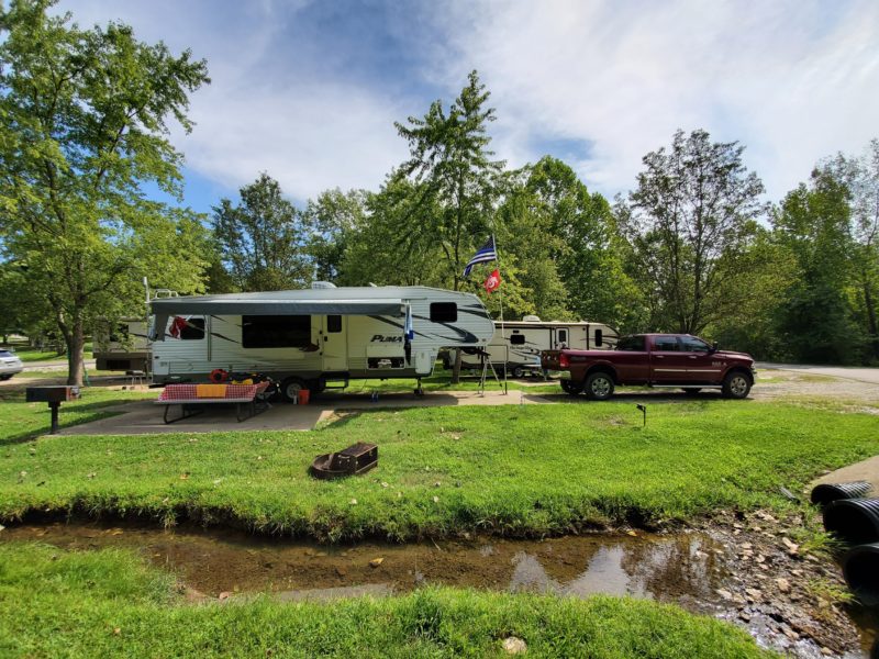 rvs and a pick up truck are parked at a campsite