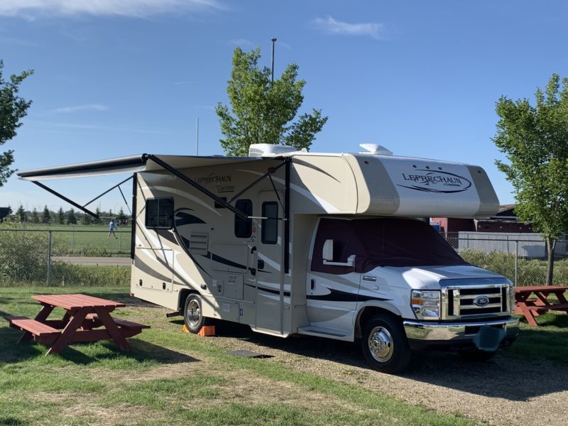an rv is parked at a campsite with red picnic tables