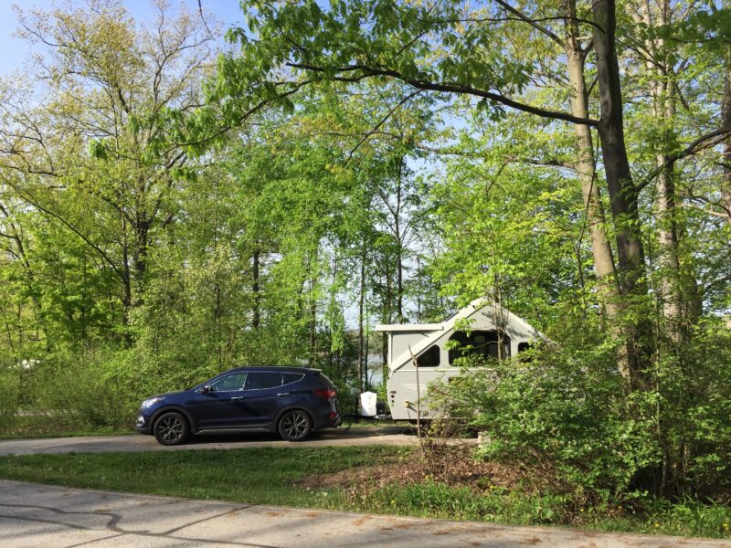 A-frame trailer parked in wooded area at a campground
