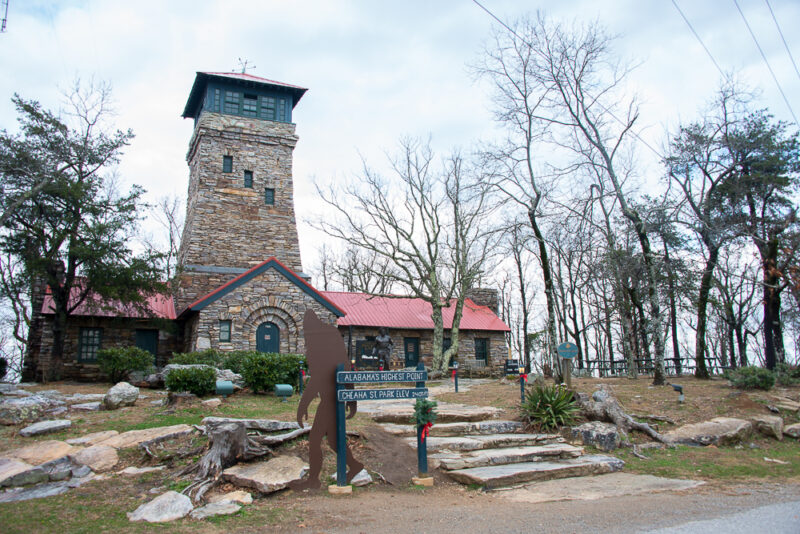 a stone building with a sasquath cutout outside and a sign that says "alabama's highest point."