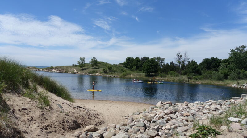 people on stand up paddle boards in a body of water with a rocky shore
