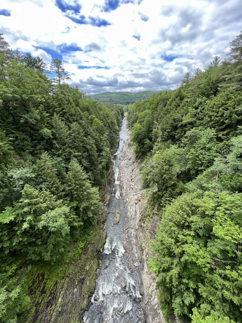 an aerial view of water running over rocks through a green forest