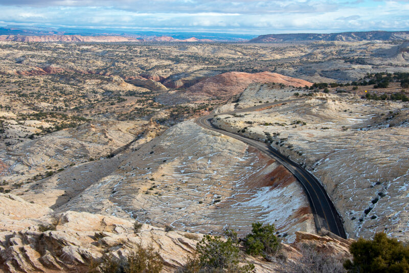 A rocky mountain landscape from above, with a paved road cutting through the center