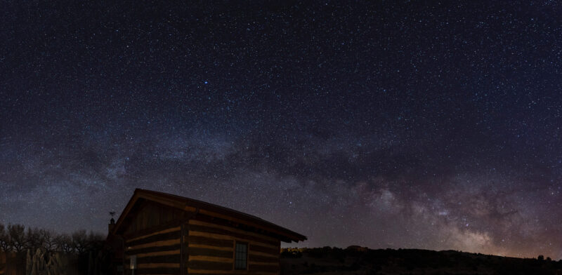 a log structure under a night sky full of stars