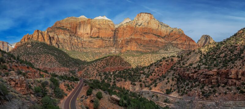 a small strip of road in the desert leading to red rock formations