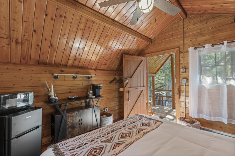 the interior of a small wooden cabin with a bed and small refrigerator