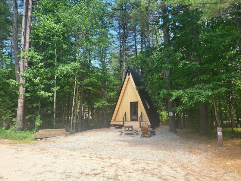 a small black and wood a-frame cabin in the woods