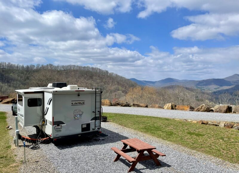 a campground with an rv parked on gravel overlooking the mountains