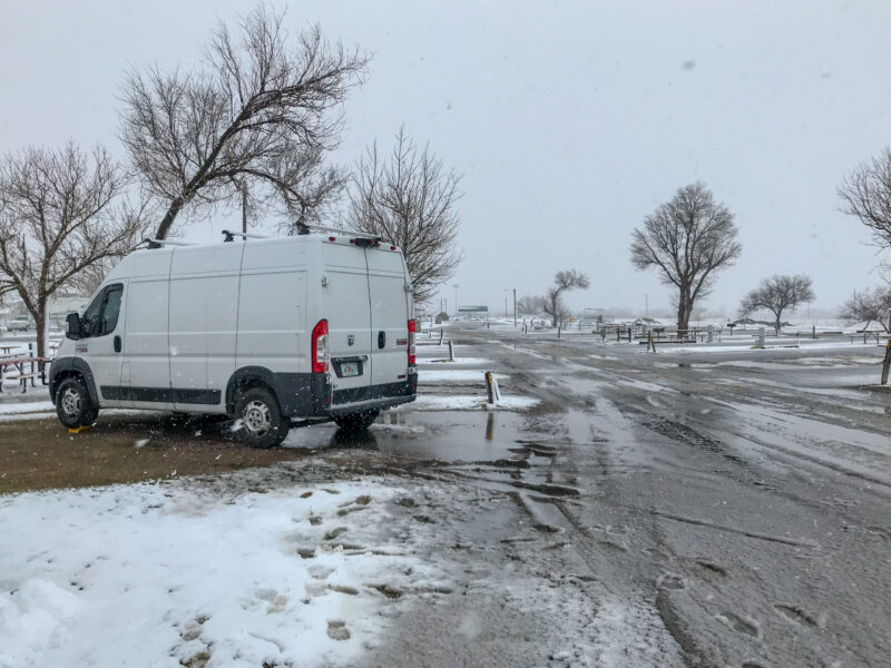 A class B motorhome sits alone in a snowy campground.