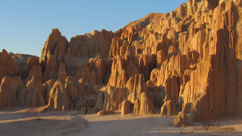 Natural rock formations reveal harsh cliffs and steep grooves carved into a rugged landscape.