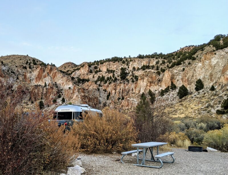 Tall brush obscures the view of an RV parked in a Southwestern campsite.