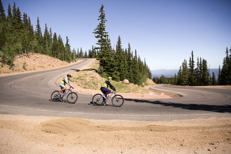 Mountain bikers race down a well-tread mountain path.