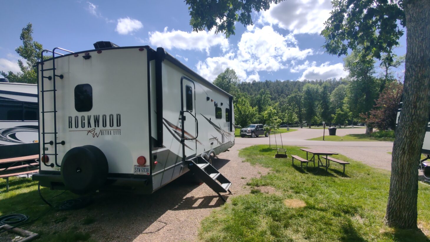 A Rockwood brand travel trailer sits beneath a leafy tree