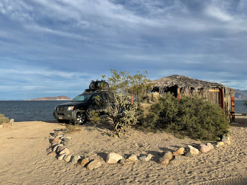 A campsite on a sandy beach is marked with a rock circle.