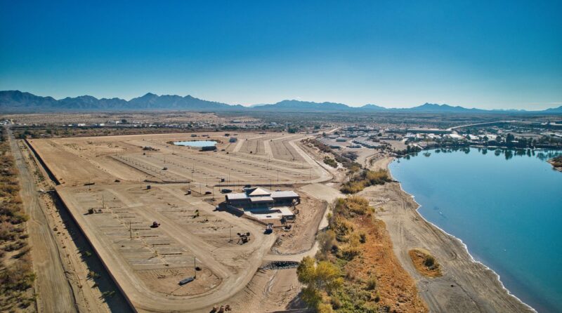 An aerial photo of River Sands RV Resort shows sandy RV parking adjacent to a river