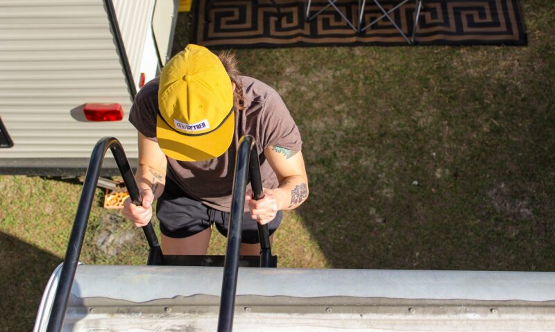 Person climbing a ladder to the roof of an RV