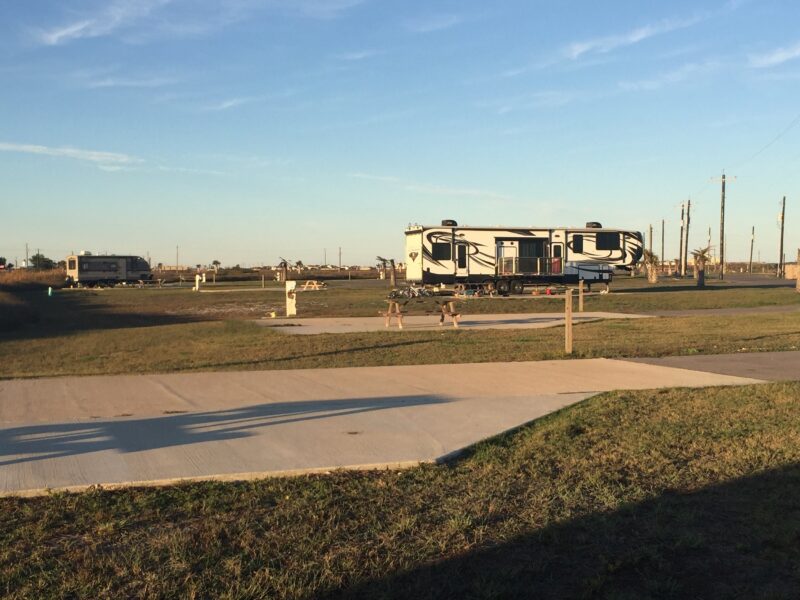 A fifth wheel RV parked at a campground with a paved site