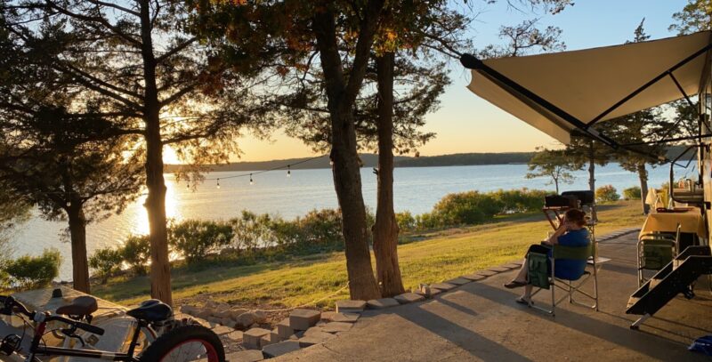 A person sitting in a chair watching the sunset over a lake